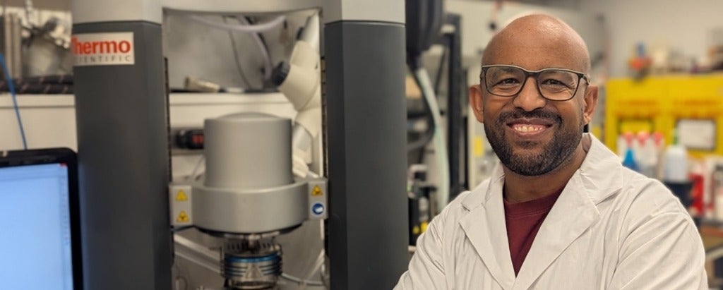 a man smiling wearing glasses and a lab coat