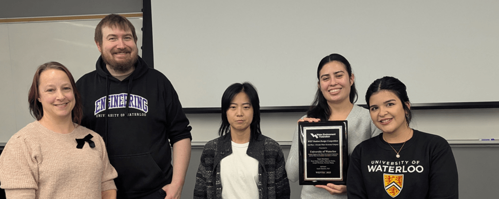Four women and a man smiling, one woman holding a plaque