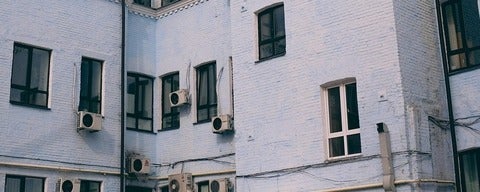 a white brick building with old fashoined black and white air conditioners sticking out of the windows