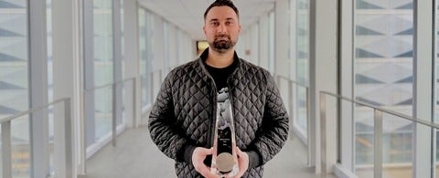 a man with a moustache and beard holding a glass award