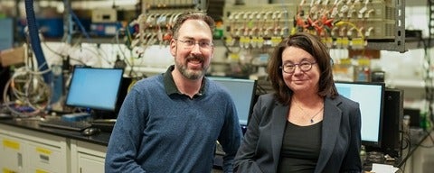 Professors Michael Pope and Linda Nazar in front of computer screens and battery testers
