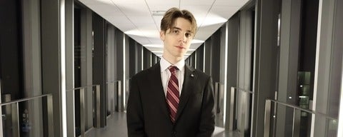 a man in a jacket and tie standing in a tunnel