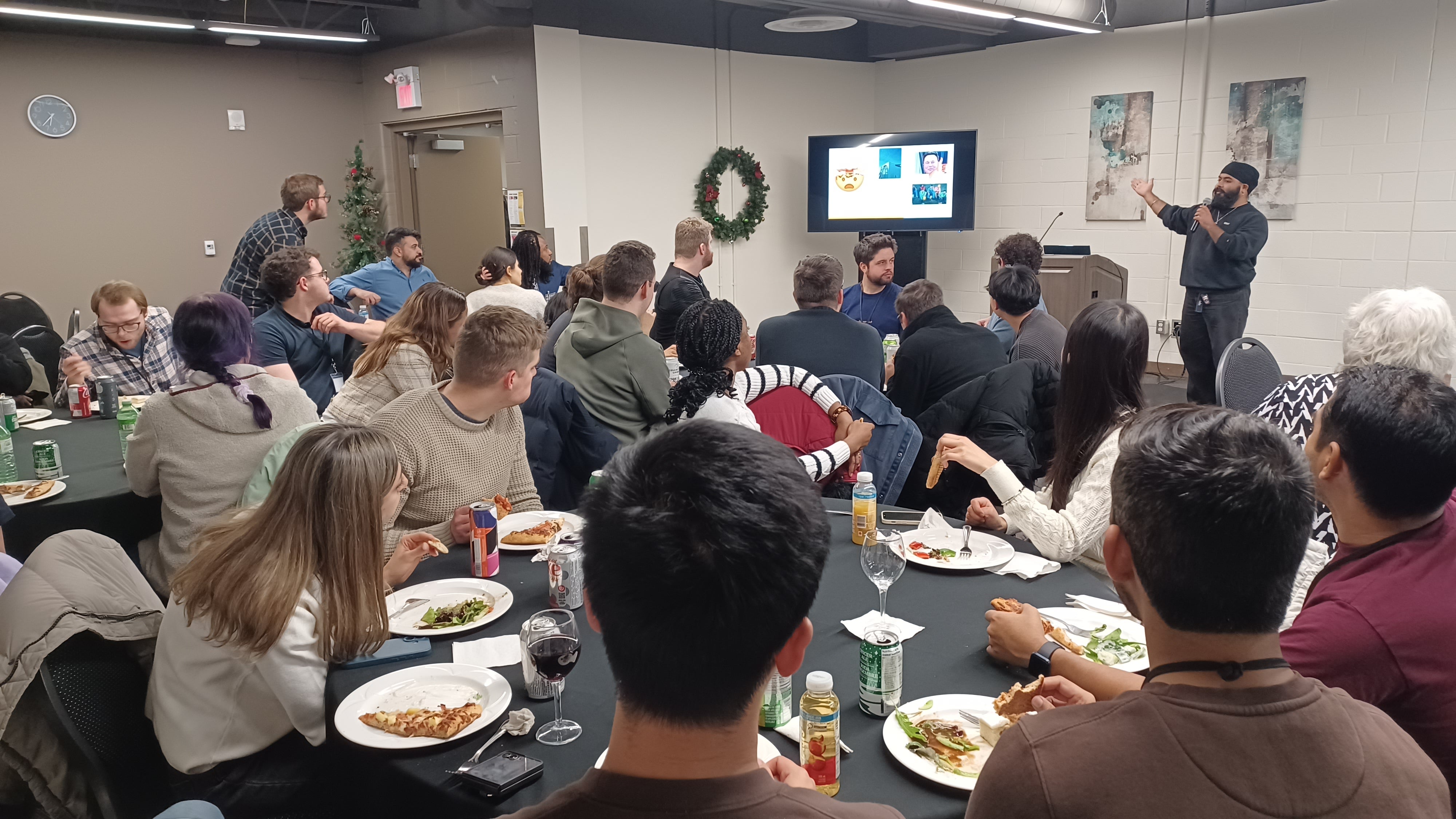 People sitting at tables a man has a microphone