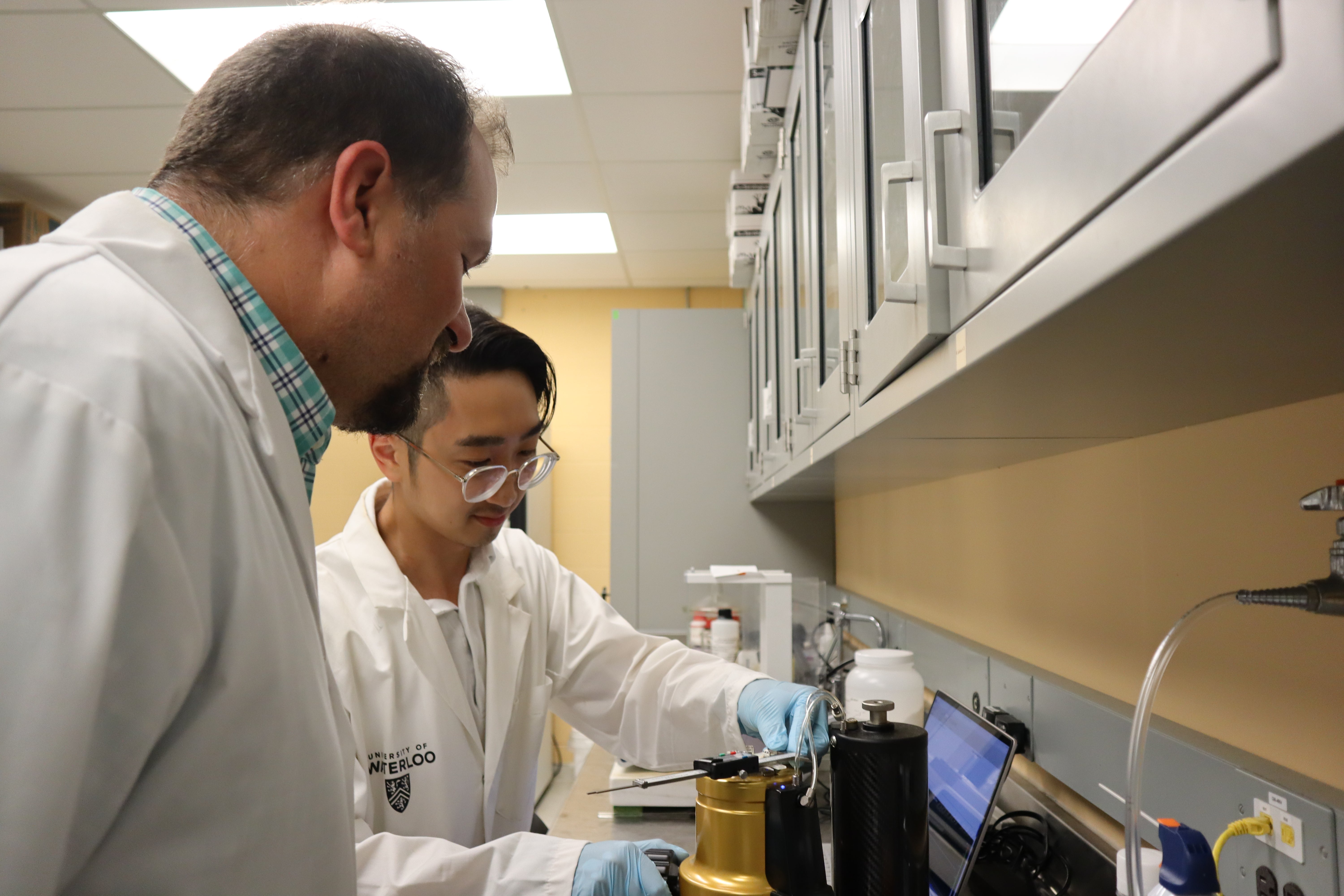 two men in lab coats looking at an instrument 