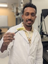 a picture of a man holding a yellow circle with tweezers