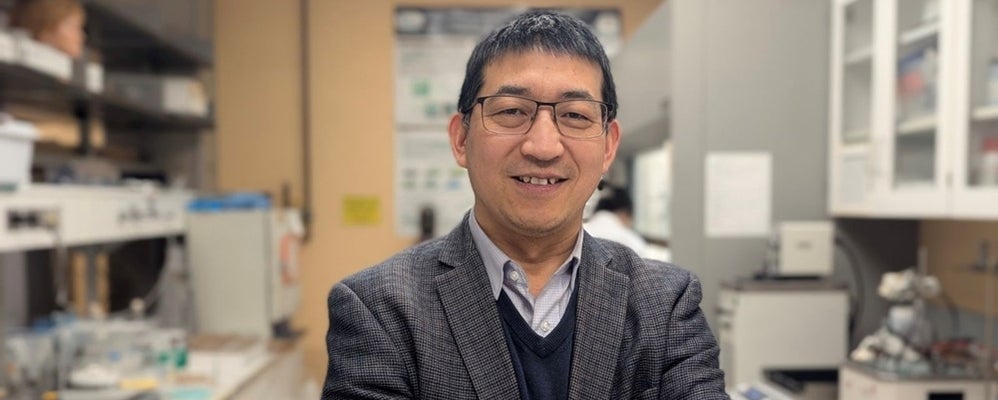 a man with black hair and glasses smiling