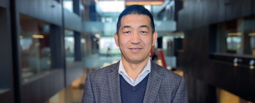 a man with black hair and a grey jacket