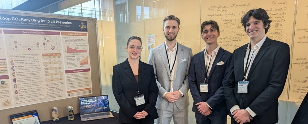 a woman and four men standing beside a poster board