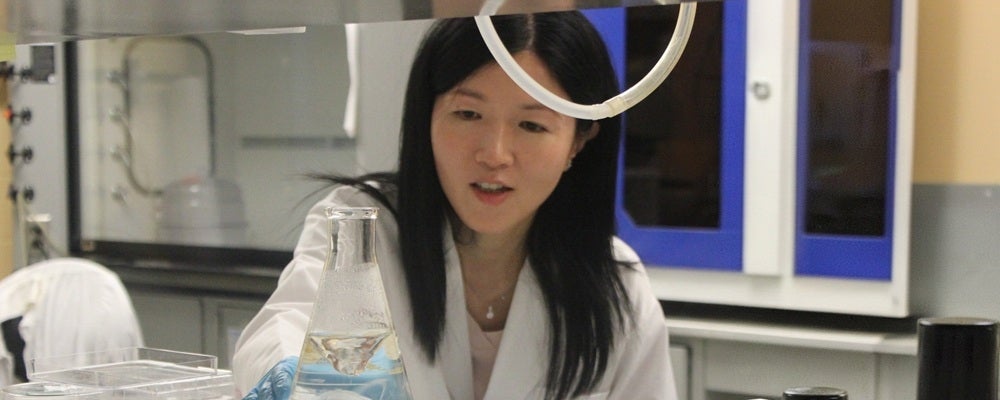 a woman with long black hair wearing a lab coat