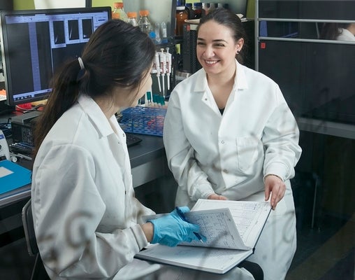 two women in lab coats and gloves