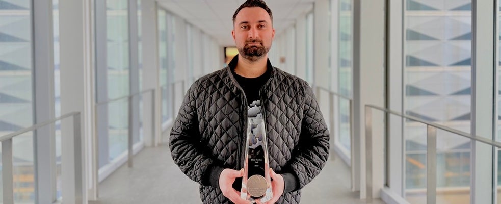 a man with a moustache and beard holding a glass award