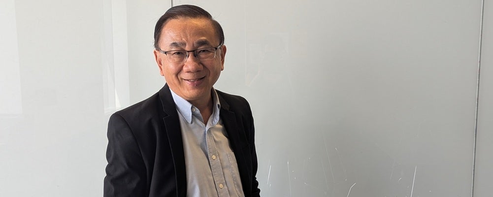 a man with black hair and glasses smiling