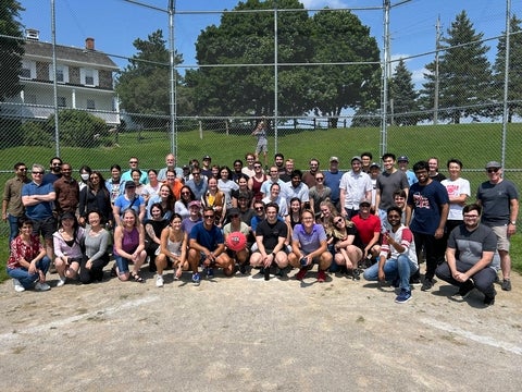 Chemistry graduate students, faculty, and staff posing on baseball diamond.