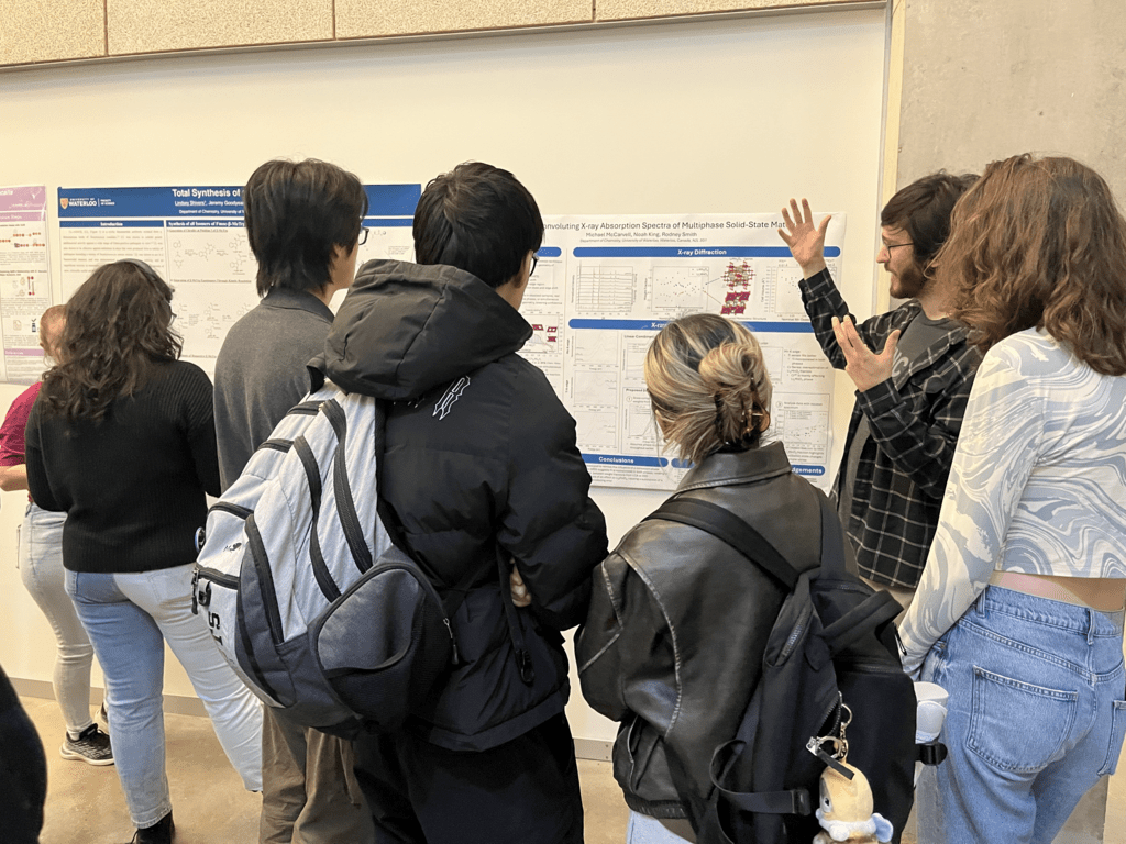 man showing a research poster to a group