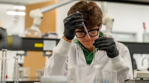 A student pipetting a sample into a test tube.
