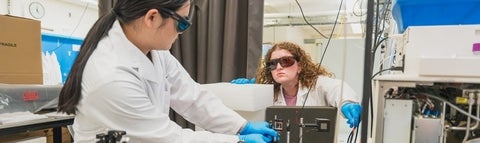 Two students operating a laser in the MNS lab.