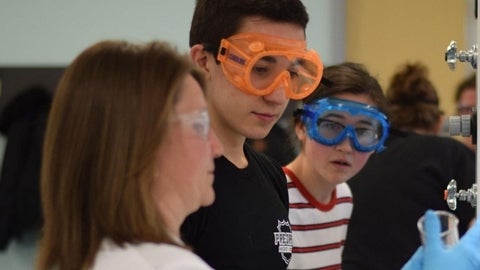 A professor with two high school students in the lab.