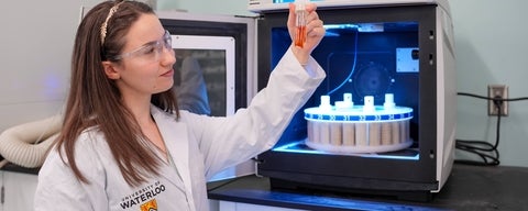 A student looking at the contents of a test tube in the lab.