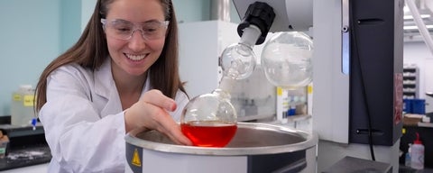 A graduate student setting up glassware over an ice bath in the lab.