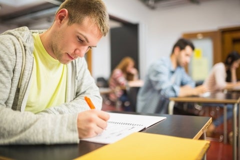 Student writing an exam in a classroom.