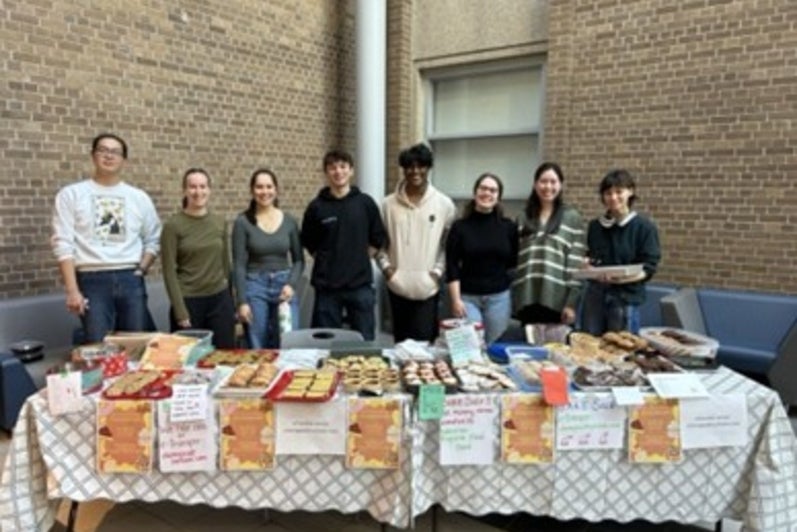 Students standing behind a table filled with baked goods.