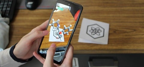 A phone showing an amino acid in artificial reality when pointed at an image of an atom.