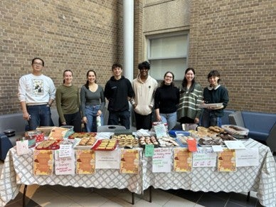 Students standing behind a table filled with baked goods.