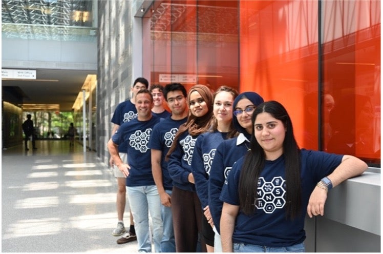MNS Society members posing along a wall in the QNC building.