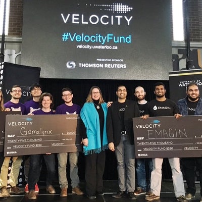 Velocity winning teams standing with cheques on stage