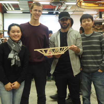 Four students holding a bridge made out of popsicle sticks
