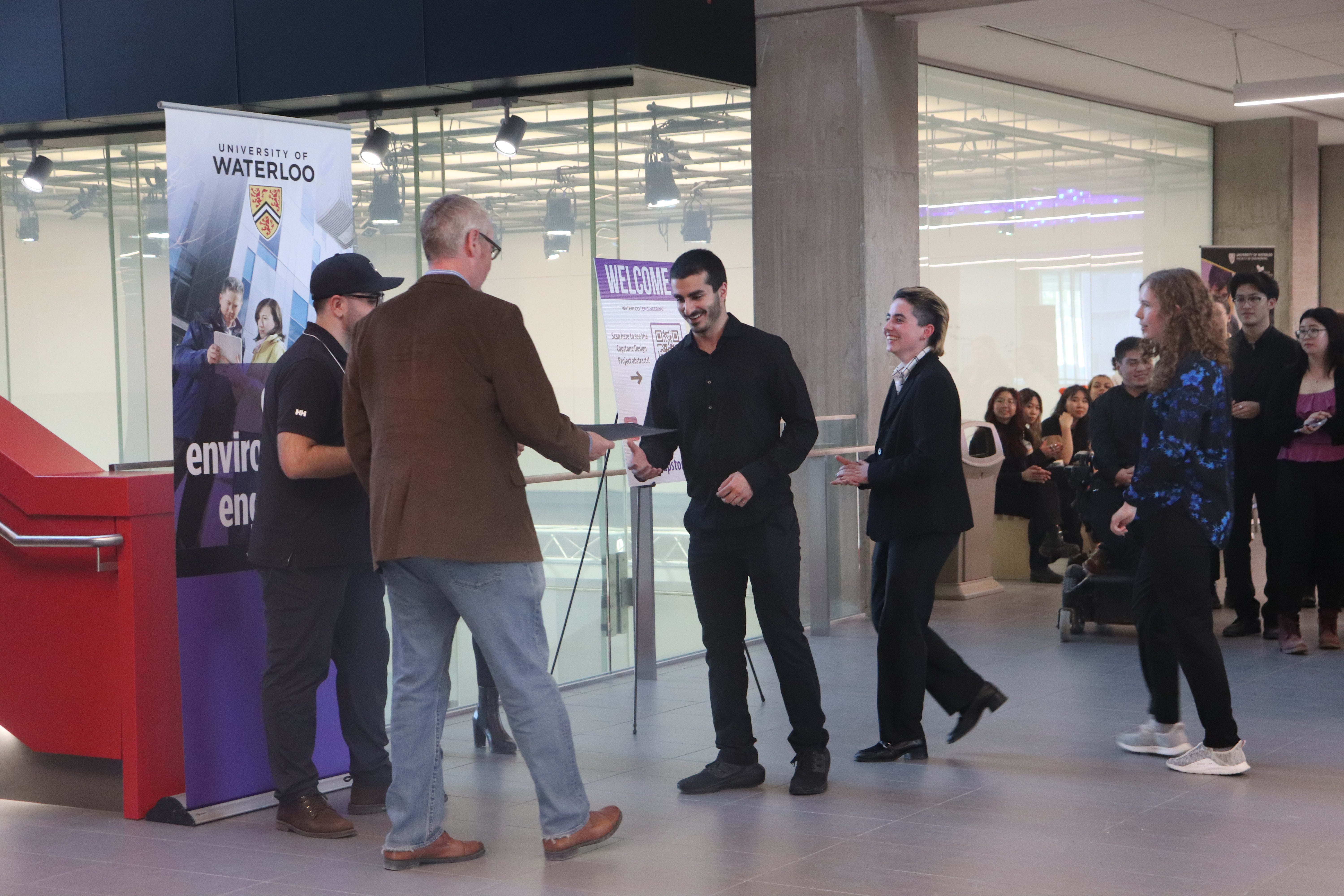 young man shaking older man in brown jackets, hand