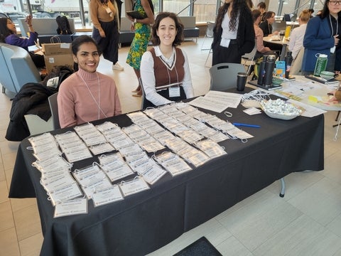 Two students sitting at a registration desk with name tags