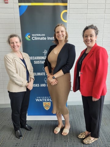 Amelia Clarke, Ena Ristic, and Sandy Little standing in front of Waterloo Climate Institute banner