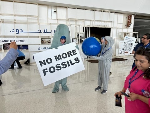 COP28 protester with "no more fossils" sign 