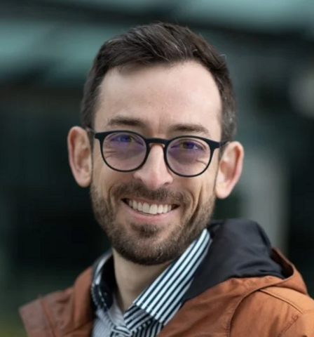 Man Smiling for Headshot in Orange Coat