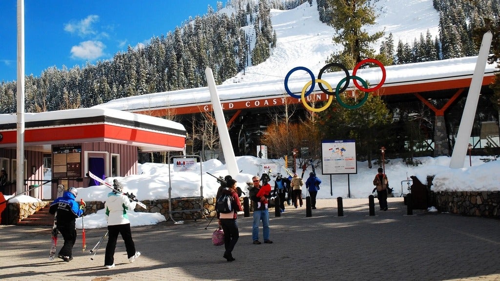 Olympic rings over top of mountain chair lift and people walking with skis to the lift