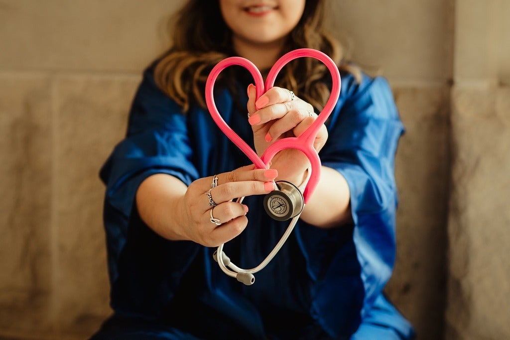 Stethoscope shaped into a heart held by two hands