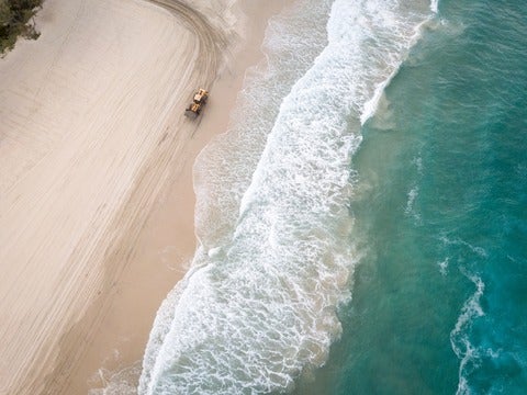 Bulldozer driving across sandy beach