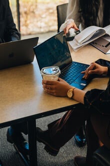 Student scrolls through laptop during meeting.
