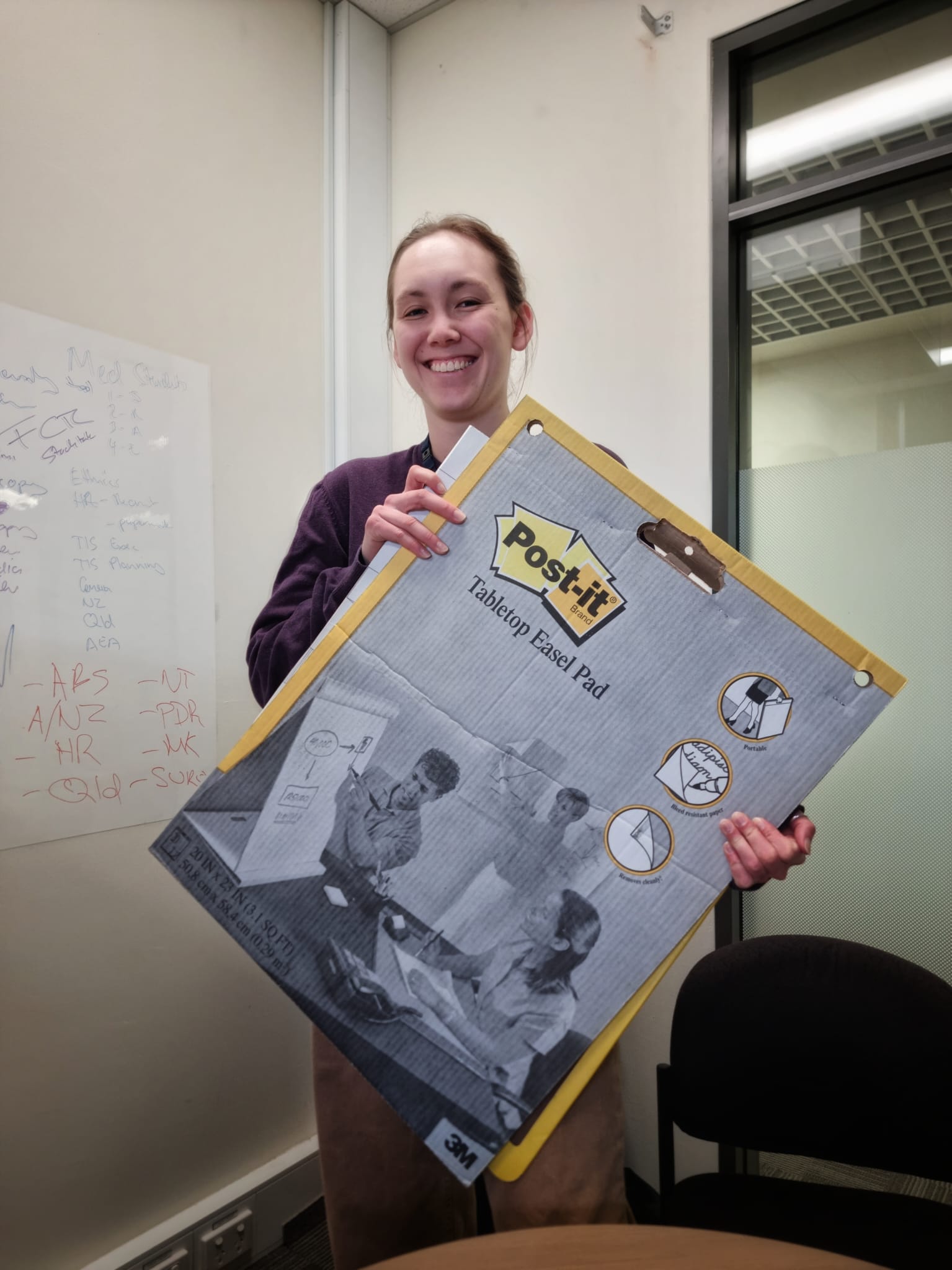 Maya Morton Ninomiya smiling while holding a poster board.