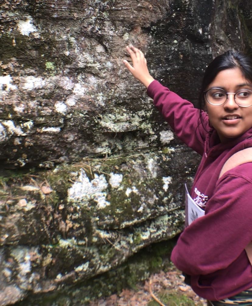 Photo of Ishani reaching her arm out on a rock wall