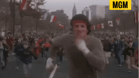 GIF of Rocky Balboa (Sylvester Stallone) running outside on the road with a crowd of children running behind him. A scene from the movie &quot;Rocky II&quot;, and the credit tag &quot;MGM&quot; located on the top right.