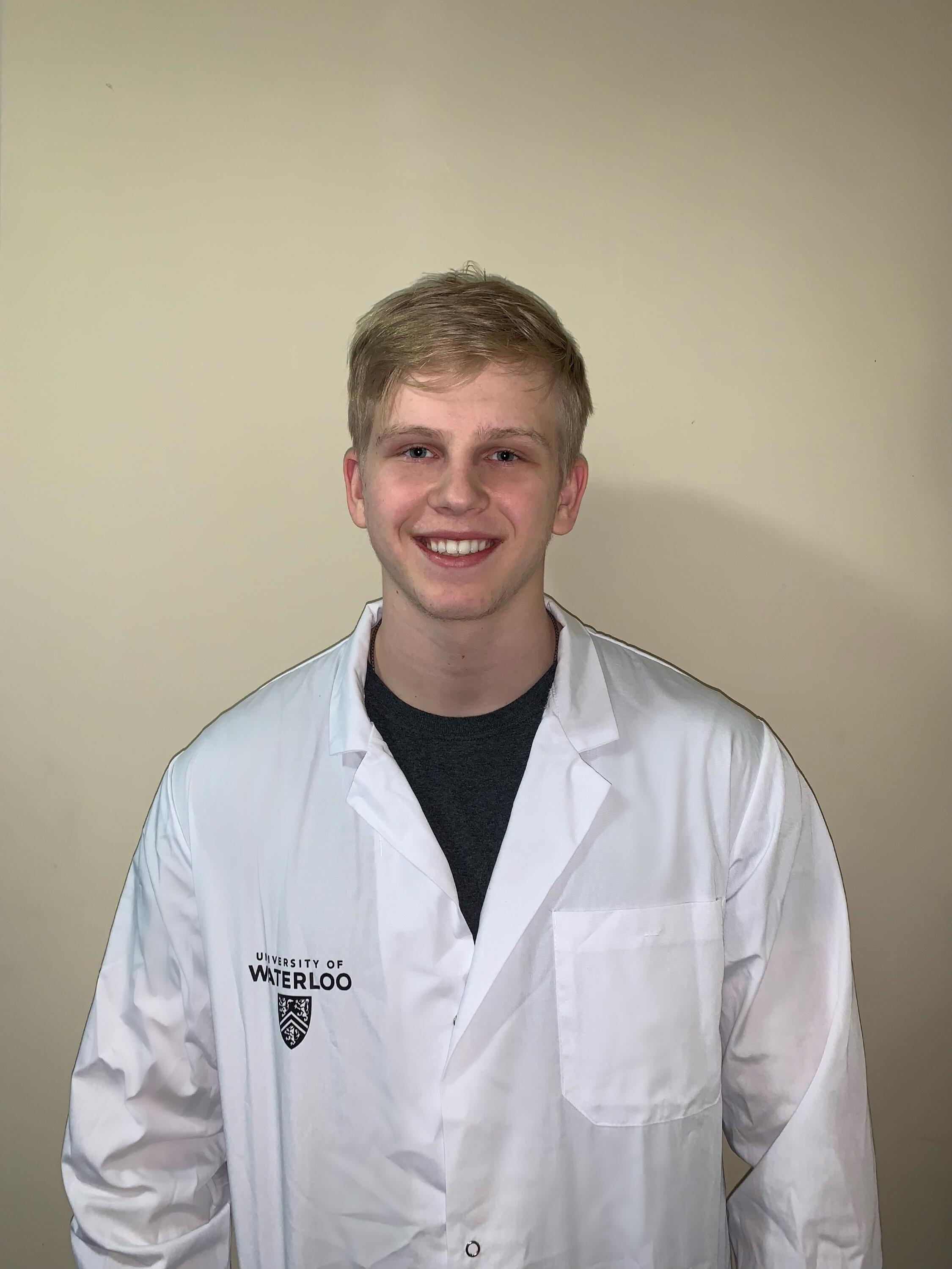A photo of Max wearing a University of Waterloo lab coat.