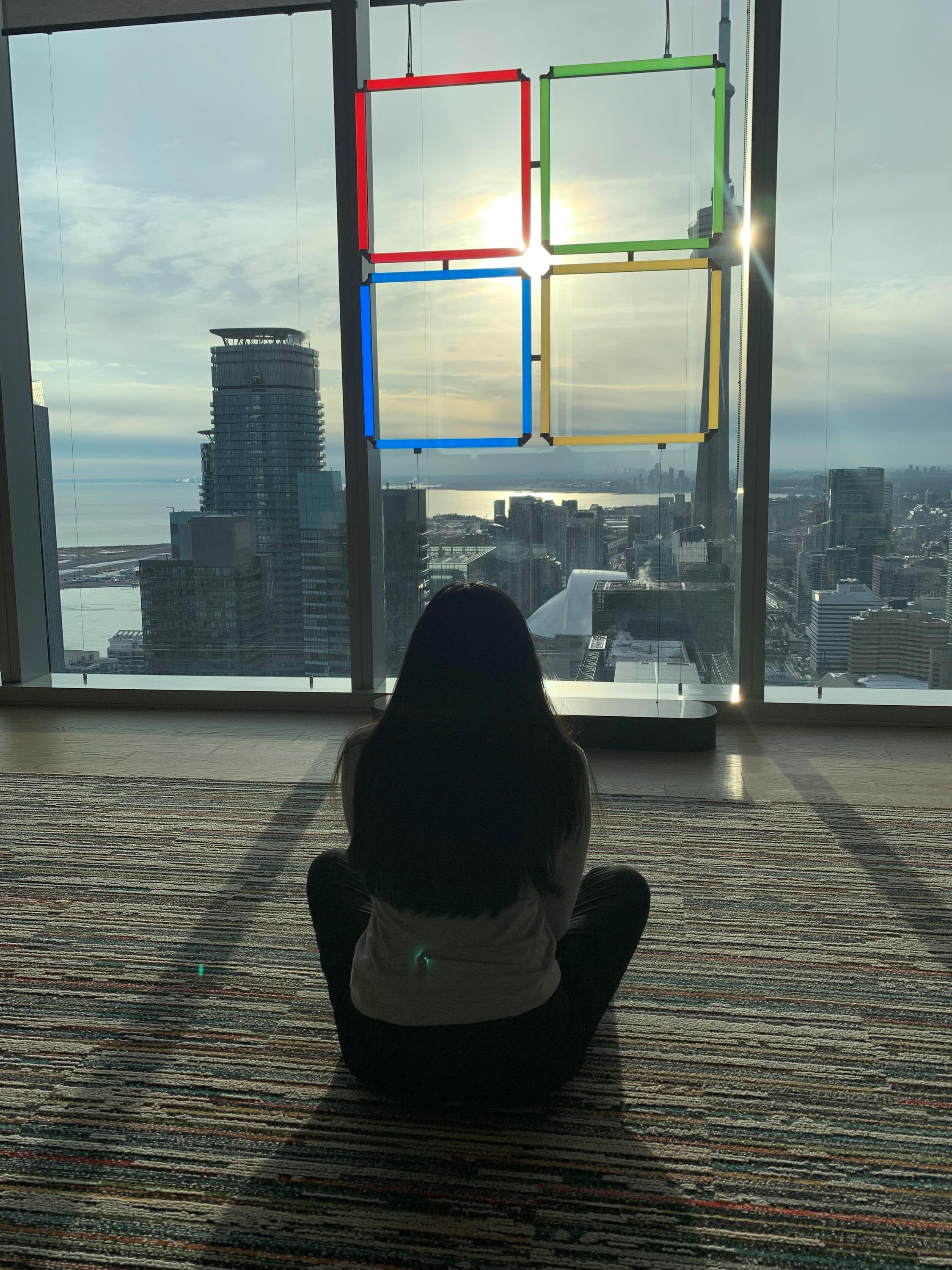 Dhruvi sitting facing a stained glass window with the Microsoft logo