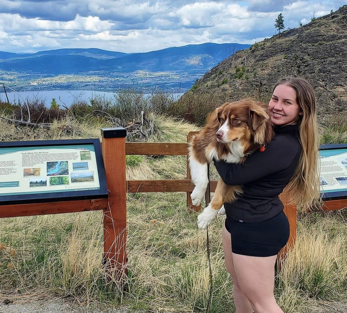 Miila standing while holding her dog by mountains