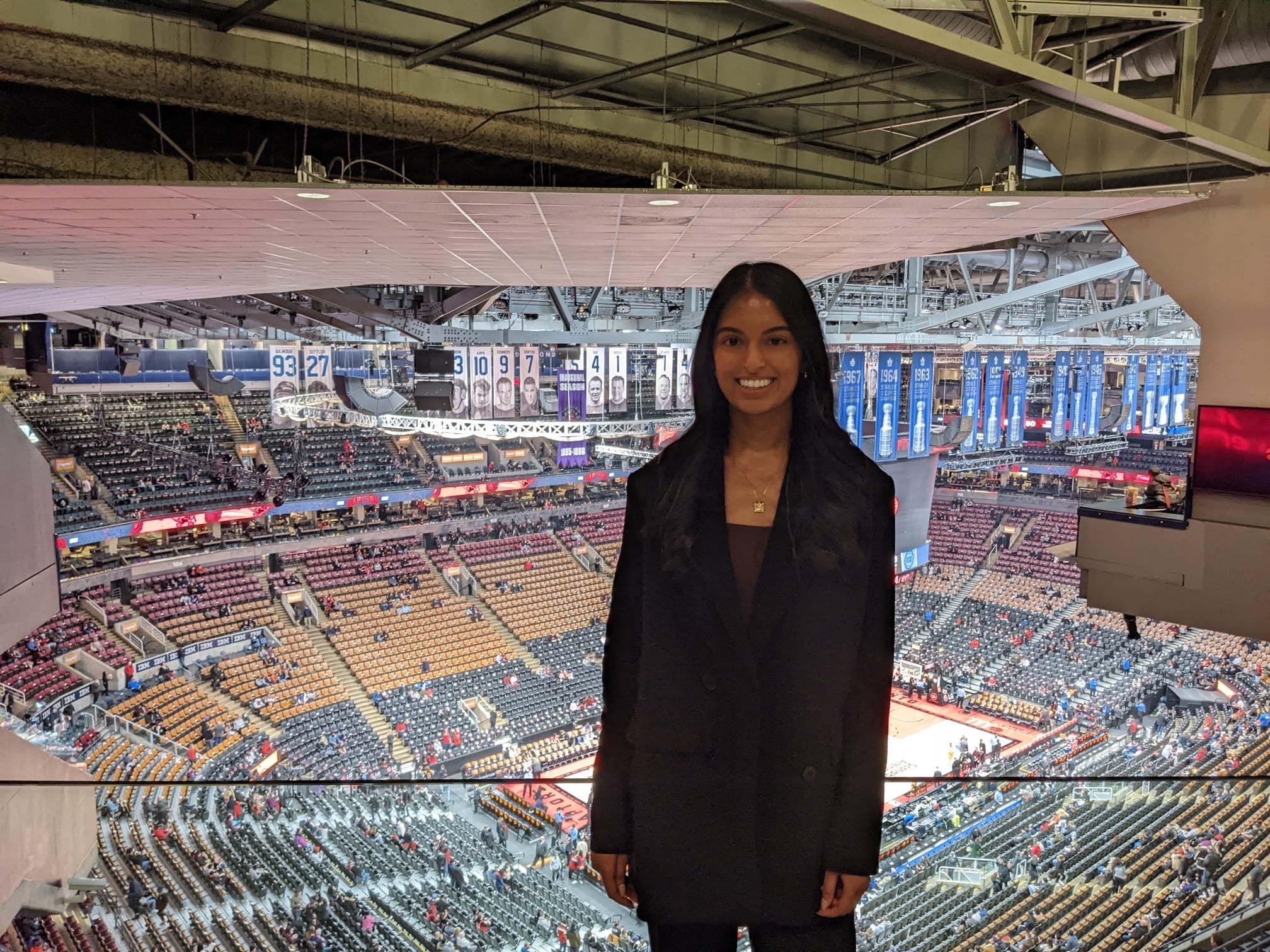 A photo of Riana standing inside the Toronto Raptors basketball arena.