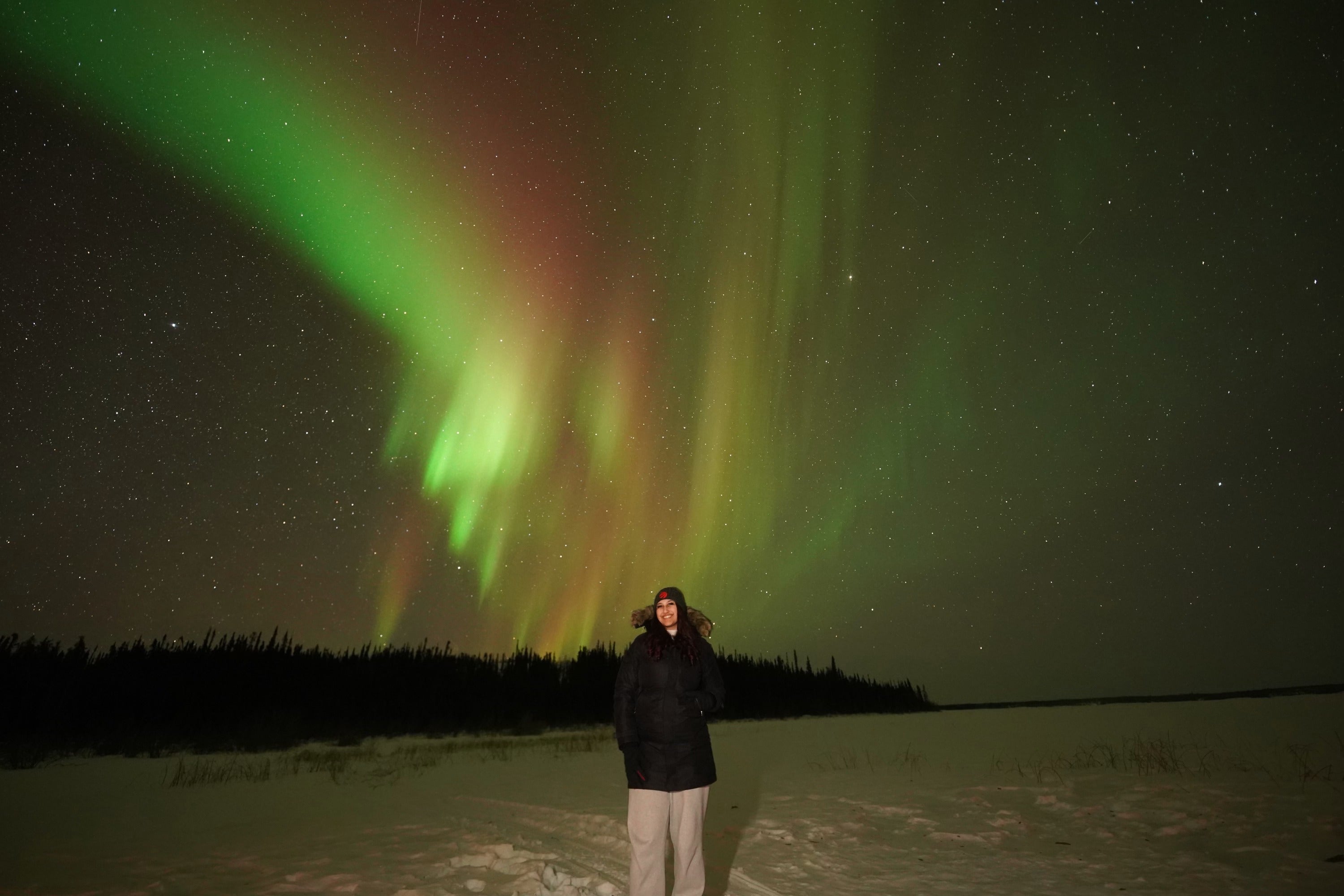 Muskaan posing with the northern lights in the background 