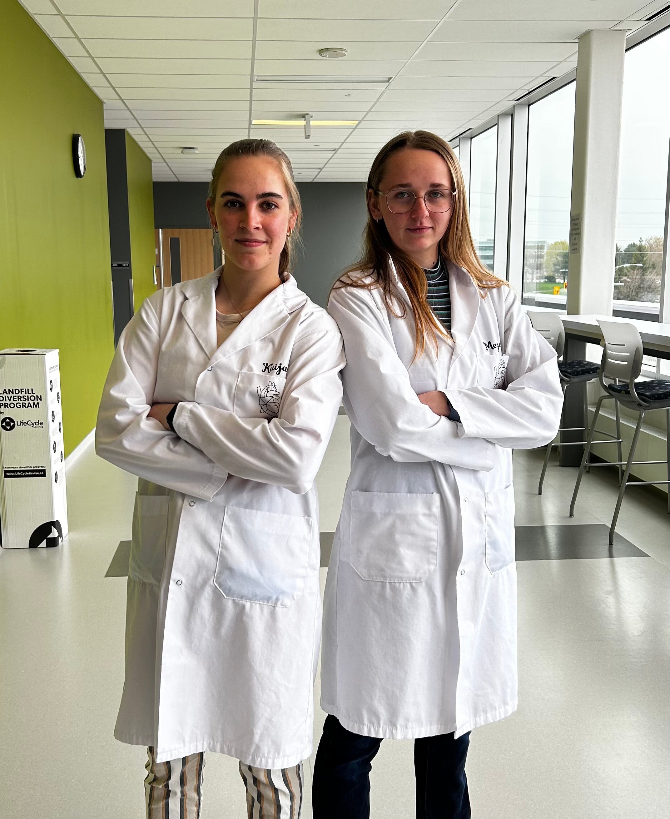 Kaija and Megan posing with their arms crossed in their lab coats. 