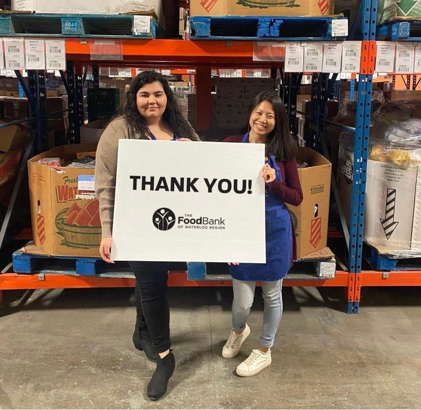 Vanessa Cerqueira and a co-worker holding a Food Bank of Waterloo Region sign reading &quot;THANK YOU!&quot;