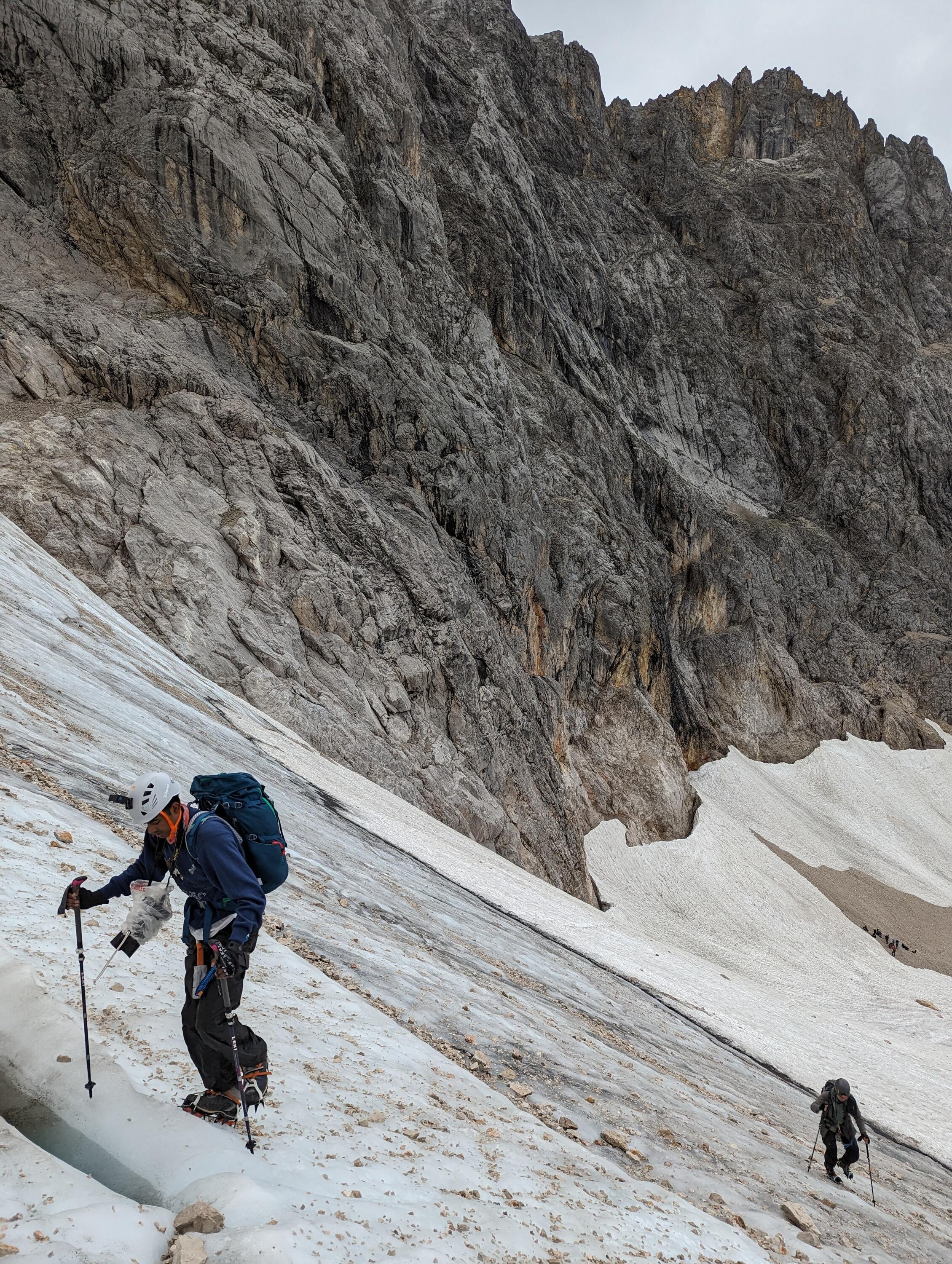Two people climbing the side of an icy mountain.